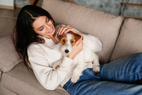woman snuggling dog on sofa
